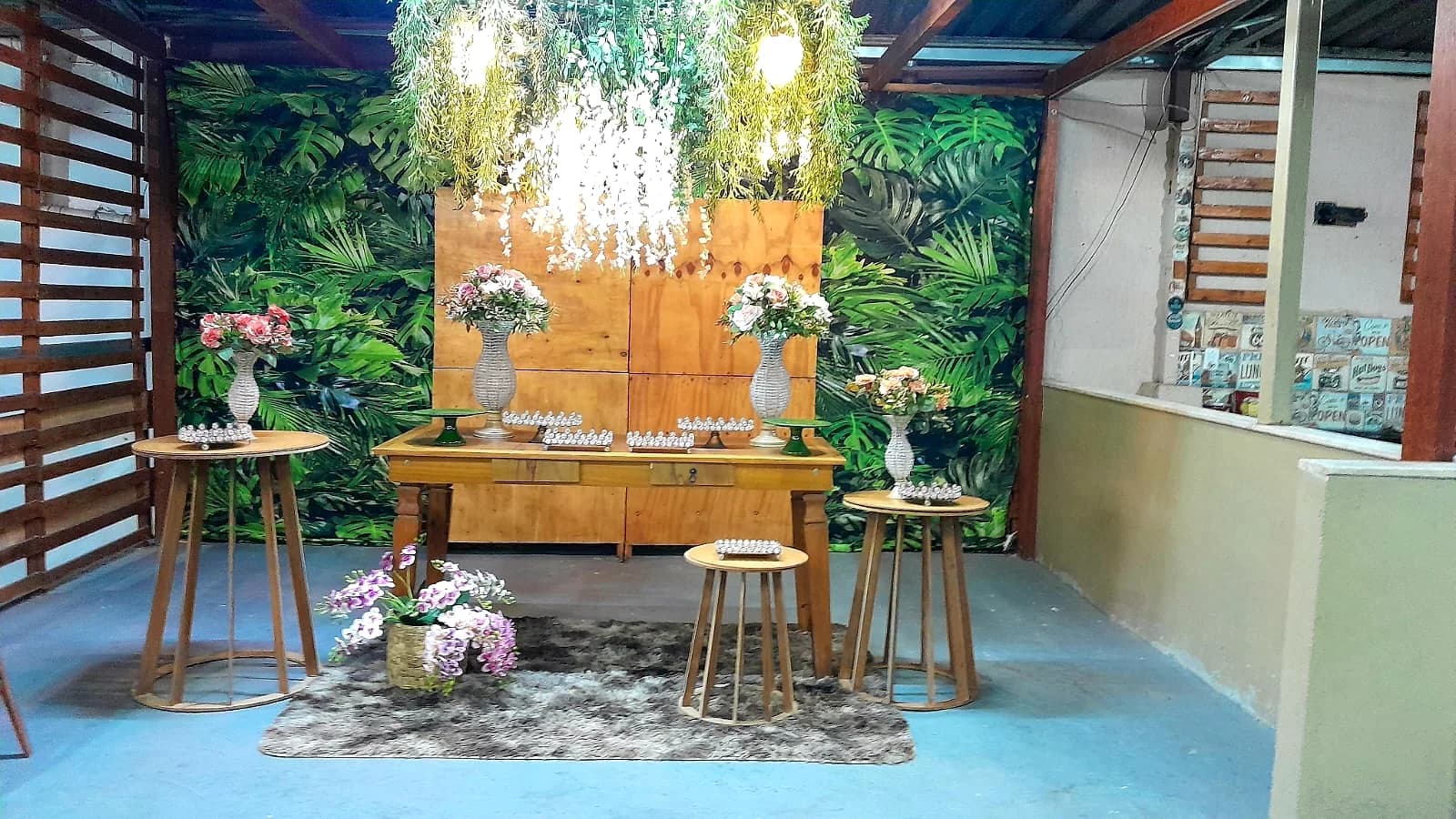 Mesa rústica de madeira com flores e painel de folhagens