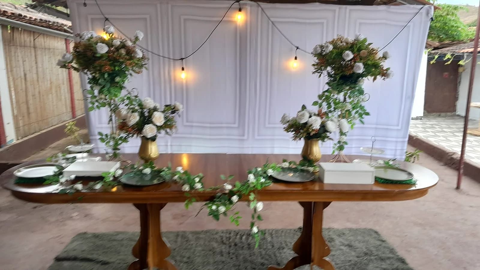 Mesa rústica com arranjos florais e luzes pendentes